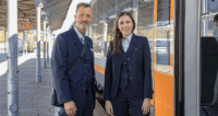 Zwei Zugbegleiter stehen am Bahnsteig vor einem Zug.